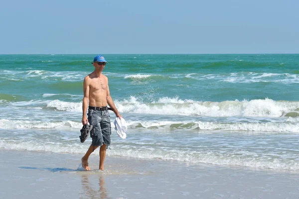 De mens loopt langs de kust. een ochtendwandeling langs de zee. — Stockfoto