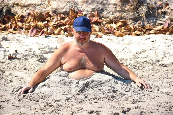 Lustige dicke Mann schlafen auf einem öffentlichen Strand. — Stockfoto