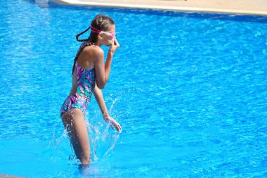 Şirin kız otelde yüzme havuzundan hoşlanıyor. Sudaki tatil köyünde bir genç. Yüzme eğitimi. Denizde çocuklarla tatiller.