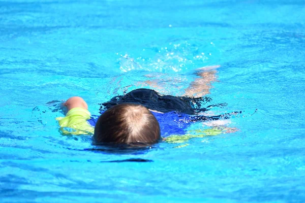 El chico flota bajo el agua en la piscina azul abierta del hotel. Buscar bajo el agua . — Foto de Stock