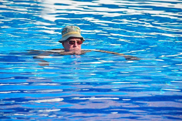 Een mannelijke gepensioneerde in het buitenzwembad van het hotel. rustige watersport voor ouderen — Stockfoto