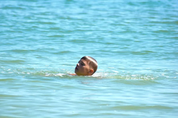 Спасаю палец в море. Маленький мальчик плавает в море один  . — стоковое фото