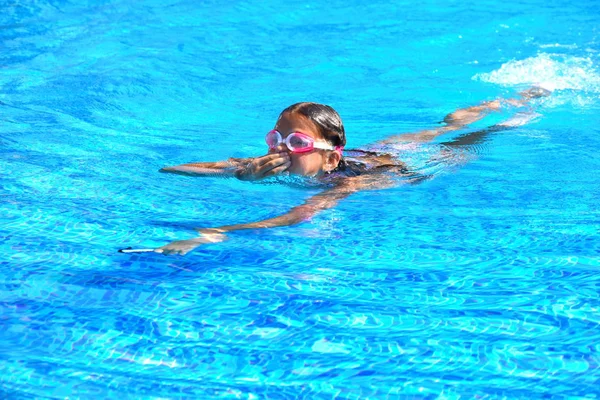 En liten flicka tycker om att simma i poolen. En vattenpool på hotellet. Sommarsemester för barn. — Stockfoto