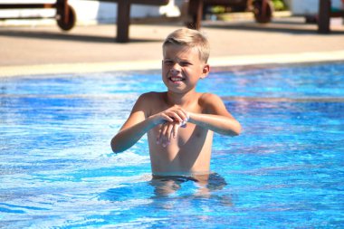 Havuzda bir bebek var. Havuzdaki bir çocuğun komik portresi. Oteldeki neşeli çocuk.