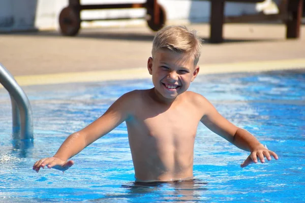 Menino na piscina. Um retrato engraçado de um rapaz na piscina. Criança alegre no hotel resort — Fotografia de Stock