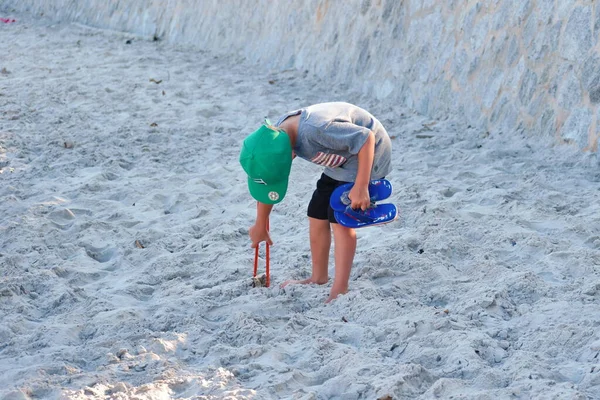 Den lille pojken städar den offentliga stranden. Rengöring av sand från skräp — Stockfoto