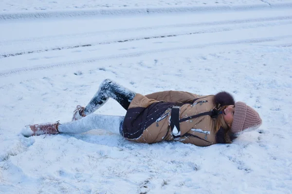 Niña niña invierno diversión en la nieve. La chica está acostada en el hielo. Disfruta del invierno y la nieve . —  Fotos de Stock