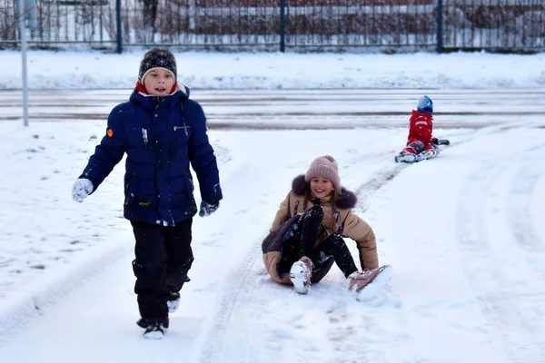Дети на снежной дороге. Счастливые дети на зимних каникулах. Веселые дети играют на свежем воздухе зимой — стоковое фото