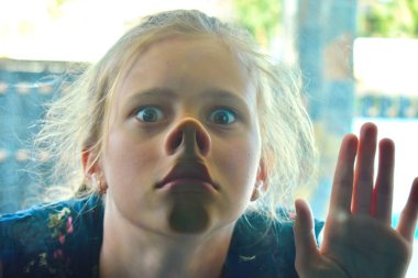 Kız pencerenin içini görüyor. Komik bir bebek. Kız dalga geçiyor..