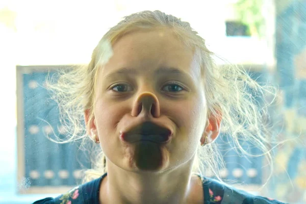 La ragazza guarda dentro la finestra. Un bambino divertente. Ragazza scherzare . — Foto Stock