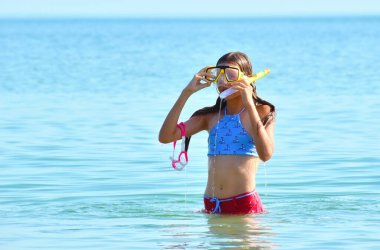 Deniz kenarındaki çocuklar. Denizde maske takan bir kız. Çocuklarla tropik bölgelerde yaz sporu