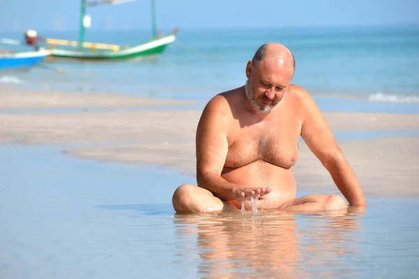 L'homme dans la flaque d'eau sur la plage. Vacances relaxantes au bord de la mer. Photo de plage amusante. Le gros dans la mer — Photo