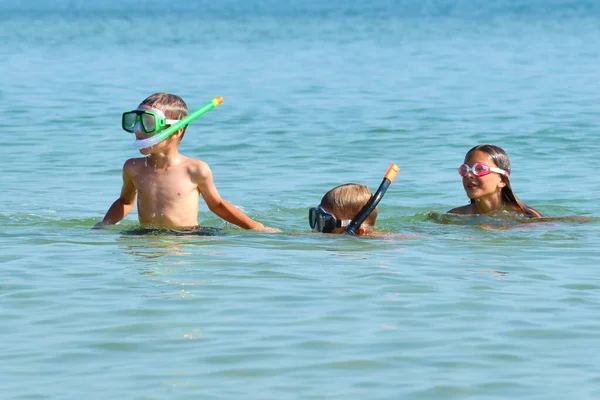 Vänliga barn i undervattensmasker på havet. Trevlig helg vid havet. Barn lär sig simma i havsvatten. — Stockfoto