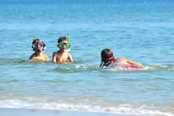 Přátelské děti v podmořských maskách na moři. Veselé svátky u moře. Děti se učí plavat v mořské vodě. — Stock fotografie