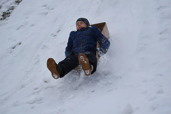 Il ragazzo sta andando a Box Hill. Allegre vacanze invernali. Ragazzo a cavallo di una collina di neve — Foto Stock