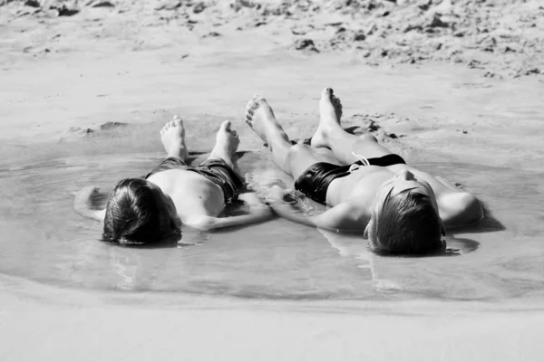 Monochrome фото. Дети лежат на песке. Мальчики загорают в воде . — стоковое фото