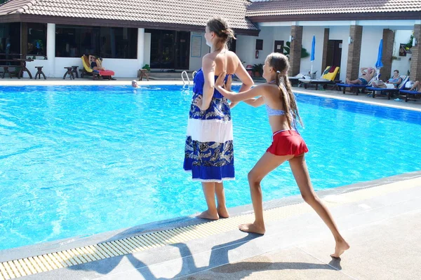 Umas férias em família cheias de diversão. Atirar a mulher para a água. A criança empurrou os pais para a piscina. Cair na água . — Fotografia de Stock