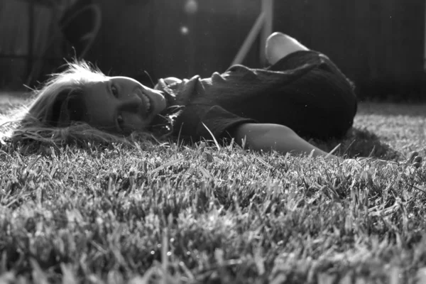 Monochromatyczne zdjęcie. Piękna młoda dziewczyna zbliżyć się na zielonej trawie w lecie. Uśmiech — Zdjęcie stockowe