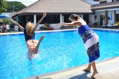 Fooling around by the pool. Girlfriend having fun on vacation. Padania from the side into the water.