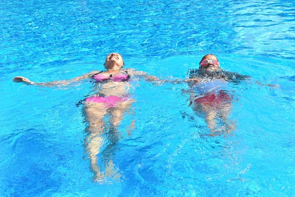 Mãe e filha se divertindo na piscina. Feliz paternidade. A mãe e a filha em um hotel nos trópicos — Fotografia de Stock