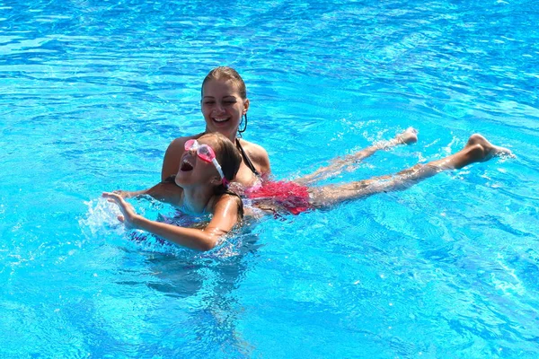 Mãe e filha se divertindo na piscina. Feliz paternidade. A mãe e a filha em um hotel nos trópicos — Fotografia de Stock