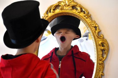 The child reflected in a distorting mirror. A fun reflection of the boy. Children's entertainment