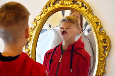 The child reflected in a distorting mirror. A fun reflection of the boy. Children's entertainment