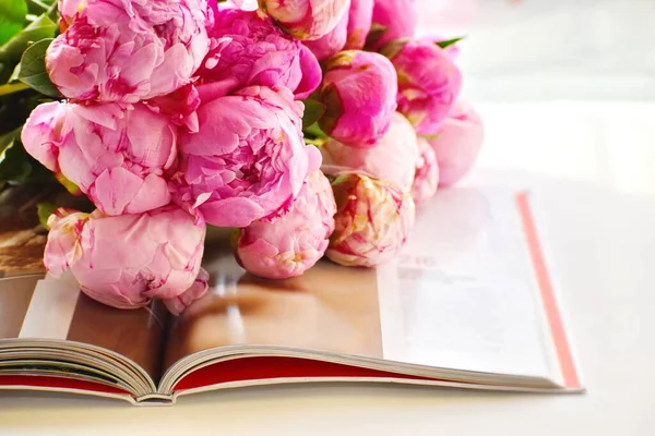 Pink peonies and book. Reading your favourite book. Flowers background. Flowers lie on open book.