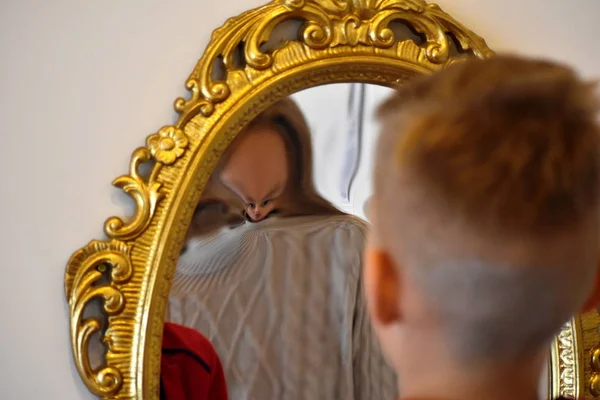 The child reflected in a distorting mirror. A fun reflection of the boy. Children's entertainment — Stock Fotó