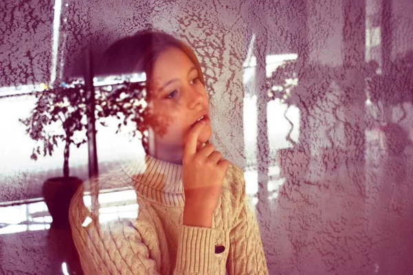 the young girl behind the transparent glass. Glare and reflection on glass. The child was conceived
