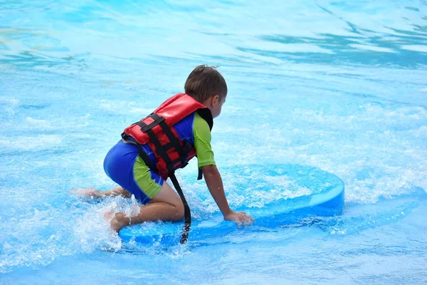 El chico en la piscina en el autdoor de verano. Vacaciones en el parque acuático. Alegre verano en el agua — Foto de Stock