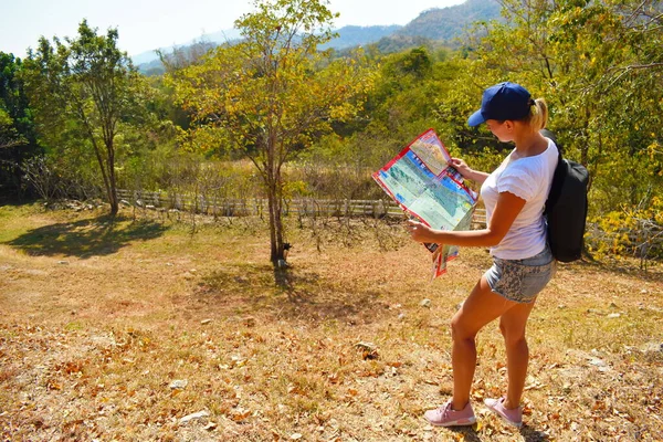 Touristin schaut auf eine Straßenkarte. Tourist in den Bergen mit Rucksack. — Stockfoto