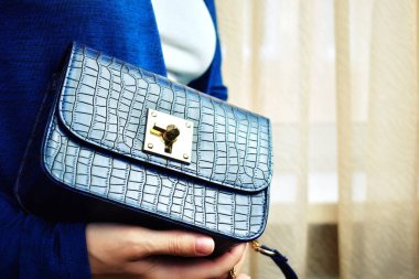 Little women's blue bag. fashion lady with a handbag in the window