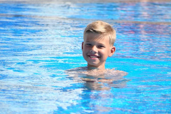 Дитячий хлопчик плаває. Хлопчик у басейні в готелі. Спортивне свято з дітьми на курорті . — стокове фото