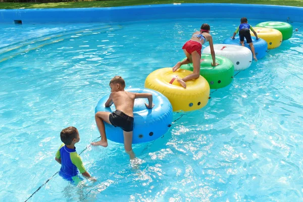 Skupina dětí v bazénu v letovisku. Veselá rodina si hraje ve vodě. — Stock fotografie