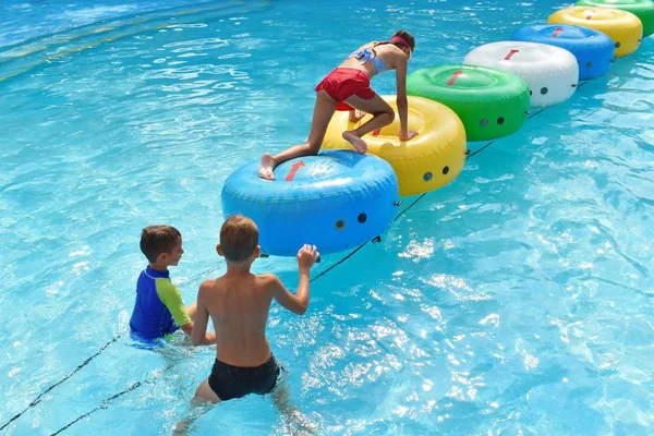 Um grupo de crianças na piscina do resort. Família alegre brincando na água . — Fotografia de Stock
