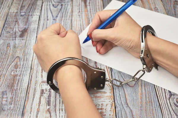 Woman in handcuffs. To sign a guilty verdict. The conviction and prison sentence. — Stockfoto