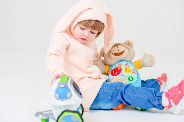 Criança menina em um fundo cinza. Bebê bonito no estúdio com brinquedo. — Fotografia de Stock