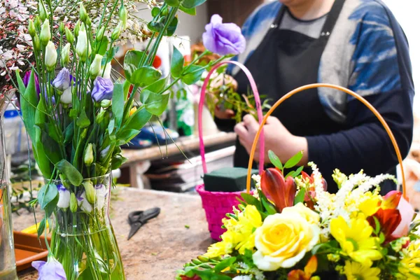 Una mujer hace un ramo fresco. Floristería recoge arreglo floral. El vendedor en floristería . —  Fotos de Stock