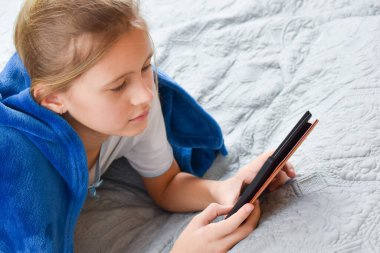 Yatakta e-kitap okuyan bir kız. Okuma aşkı.