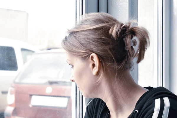 Aislamiento doméstico. La mujer mira con nostalgia afuera. Quédate dentro por mucho tiempo. . — Foto de Stock