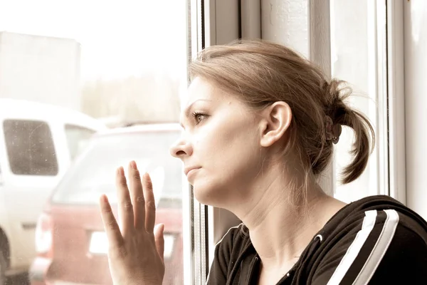 Home insulation. The woman looks longingly outside. Stay inside for a long time.