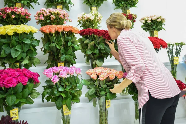 Квітковий холодильник в магазині. вітрина з вазами троянд. Флорист на роботі — стокове фото