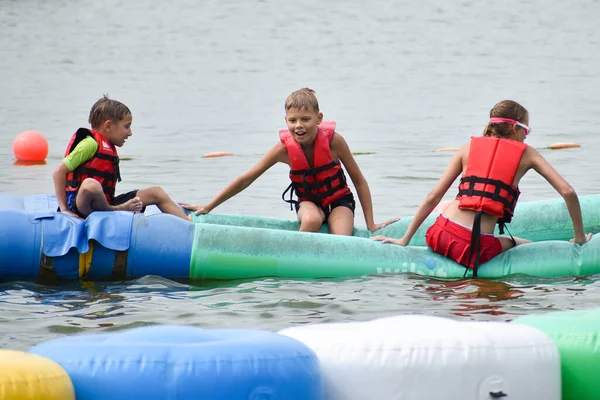 Kinder in Wasserjacken, Wasseraufblasbare Fahrgeschäfte. Organisation von Sommerotdyha für Kinder — Stockfoto