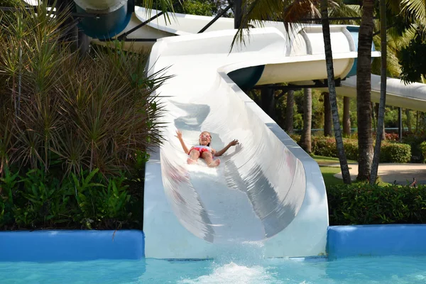 Child girl on the waterslide in the pool in the summer — Stock Photo, Image