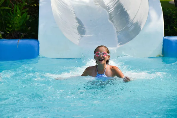 Child girl on the waterslide in the pool in the summer — Stock Photo, Image