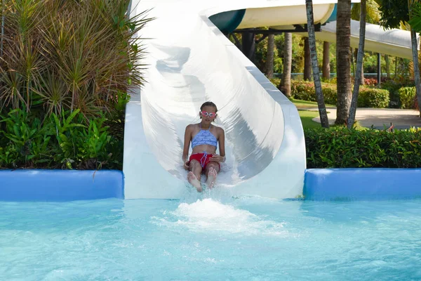Child girl on the waterslide in the pool in the summer — Stock Photo, Image