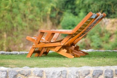 Parkta rahatlamak için iki tahta sandalye. Yeşil çimlerin üzerinde rahatlatıcı bir tatil yeri.
