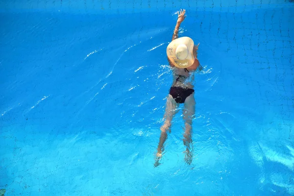 Mujer con sombrero descansando en la zona de la piscina . — Foto de Stock