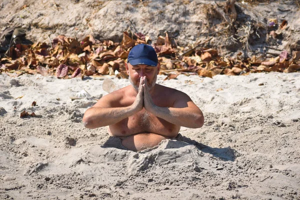 A férfi eltemetve a homokgödörben. Turista a strandon meditálva — Stock Fotó